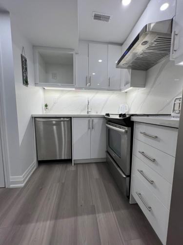 a kitchen with white cabinets and stainless steel appliances at Cozy 2 Bedrooms Modern Basement Suite with Private entrance, Kitchen and parking in Mississauga