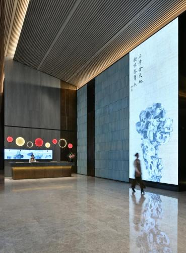 a man walks through a lobby of a building at JOYA Shanghai Gubei in Shanghai