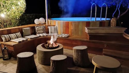 a patio with a fire pit and a table and stools at DREAM house by the sea in Epanomi