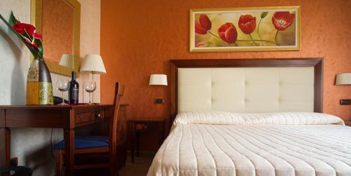 a bedroom with a bed and a desk and a vase of flowers at Hotel Flora in Noto