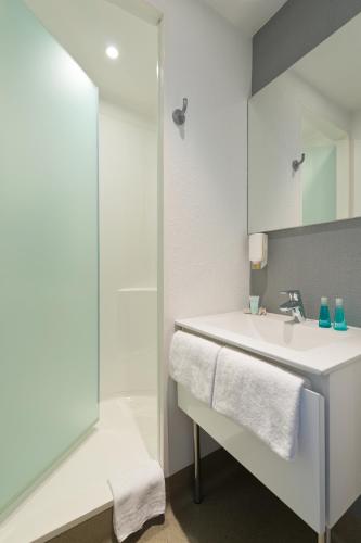 une salle de bain blanche avec un lavabo et une douche dans l'établissement ibis budget Cannes Centre Ville, à Cannes