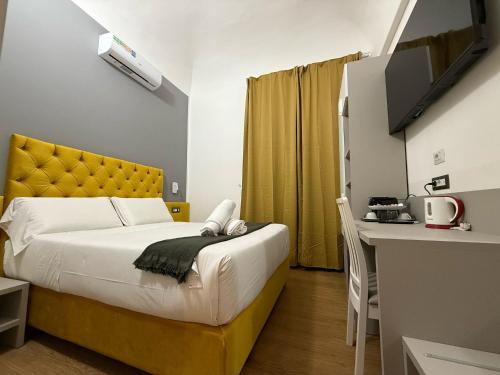 a bedroom with a bed with a yellow headboard and a desk at Conte GuestHouse in Rome