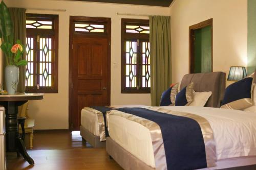 a bedroom with a bed and a table and windows at Penang Story LINN House in George Town
