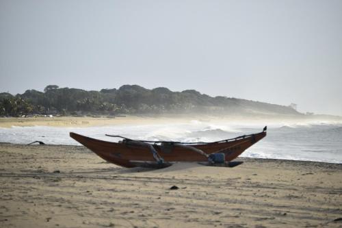 a boat sitting on a beach next to the ocean at Villa Arugam Bay in Arugam Bay