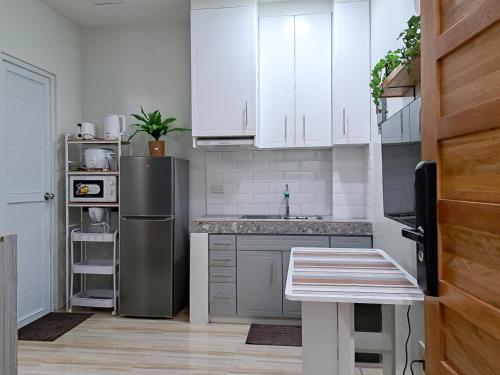 a kitchen with white cabinets and a stainless steel refrigerator at Sunset Suite Condo Style Stay with Motor Parking in Santo Cristo