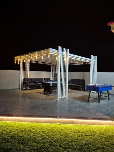 a pergola with couches and tables under it at night at Valley View farm in Maghribīyah