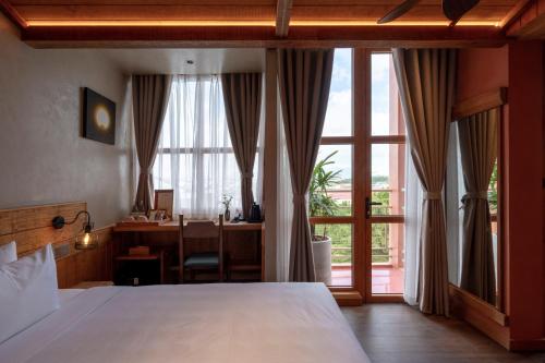 a bedroom with a bed and a desk and a window at The Pink Boutique Hotel in Da Lat