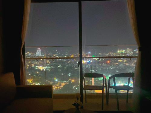 a view of a city from a window with two chairs at Erica's House - Oceanview The Sóng Apartment Vũng Tàu Nghỉ Dưỡng Biển Cao Cấp 5 Sao - The Song Vung Tau Condotel 5 Star Beach View Apartment in Vung Tau