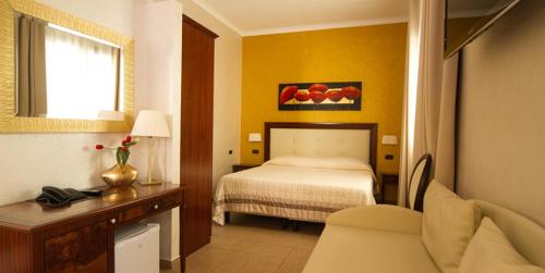 a bedroom with a bed and a desk and a chair at Hotel Flora in Noto