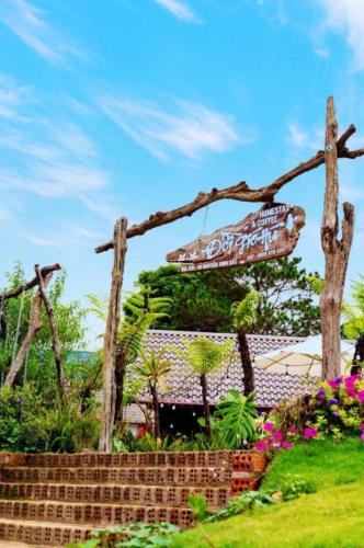 a sign for a restaurant in a garden at Đồi Gió Hú Homestay & Coffee Măng Đen in Kon Von Kla