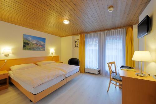 a bedroom with a bed and a desk and a television at Hotel Rössli in Interlaken