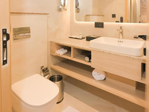 a bathroom with a sink and a toilet and a mirror at Arrival Hotel in Hyderabad
