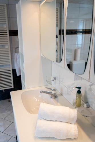 a bathroom with a sink with a mirror and towels at Schlafen zur Brauerei St. Johann in Nesslau