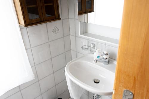 a white bathroom with a sink and a mirror at Schlafen zur Brauerei St. Johann in Nesslau