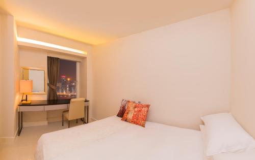 a bedroom with two beds and a desk and a window at Kowloon Harbourfront Hotel in Hong Kong