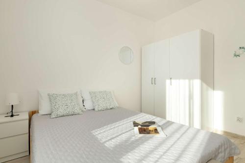 a white bedroom with a bed with a book on it at Spacious Apartment with Balcony in Gdańsk by Rent like home in Gdańsk