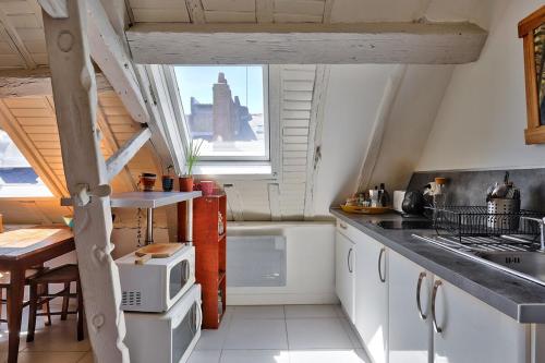 une cuisine avec des armoires blanches, un évier et une fenêtre dans l'établissement T1 bis charmant Place Graslin, à Nantes