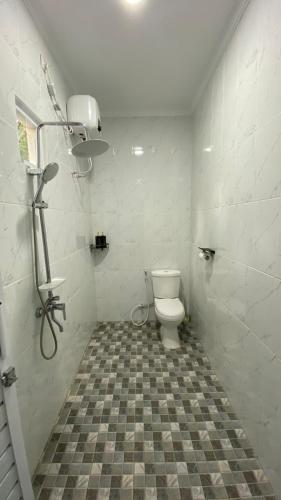 a bathroom with a toilet and a tiled floor at Asaan homestay in Ciburial