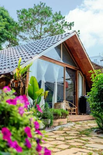 a cottage with a conservatory with pink flowers at Đồi Gió Hú Homestay & Coffee Măng Đen in Kon Von Kla