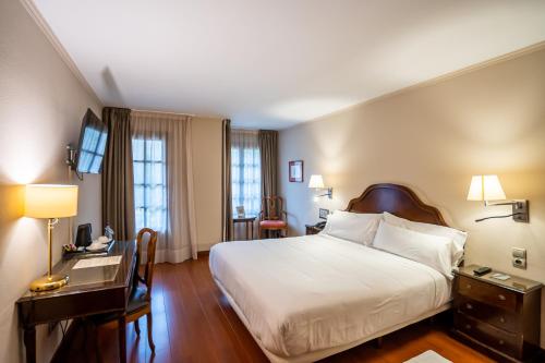 a hotel room with a large bed and a desk at Abba Xalet Suites Hotel in Sispony