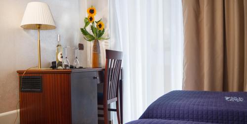 a bedroom with a bed and a table with a vase of sunflowers at Hotel Flora in Noto
