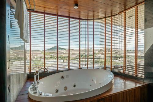 a bath tub in a room with a large window at Villa Nam Hồ 3 Phòng Ngủ in Khu Chi Lăng