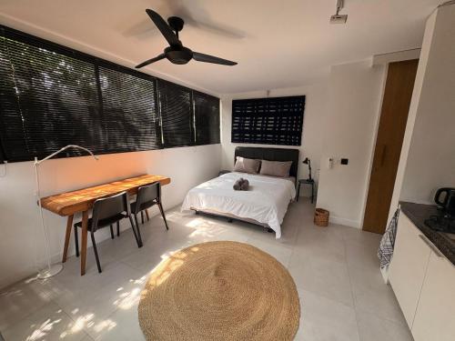 a bedroom with a bed and a table and a ceiling fan at The Drupadi Apartments Studio Gordy in Seminyak