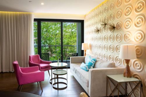 a living room with a couch and two pink chairs at The Fives Downtown Hotel & Residences, Curio Collection by Hilton in Playa del Carmen