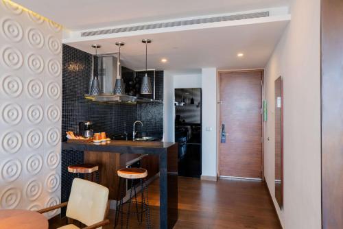 a kitchen with a bar with stools and a table at The Fives Downtown Hotel & Residences, Curio Collection by Hilton in Playa del Carmen