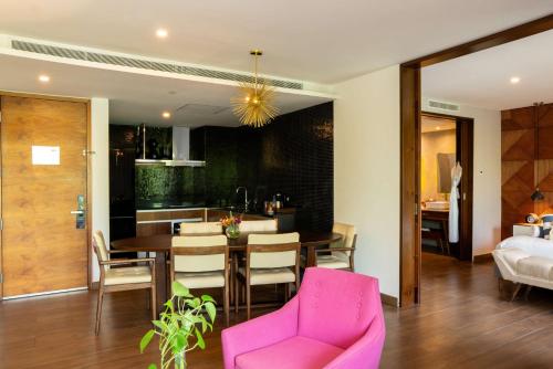 a kitchen and dining room with a table and pink chairs at The Fives Downtown Hotel & Residences, Curio Collection by Hilton in Playa del Carmen