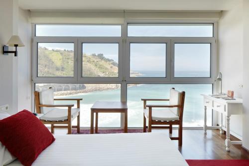a bedroom with a bed and a table and chairs at Saiaz Getaria Hotela in Getaria