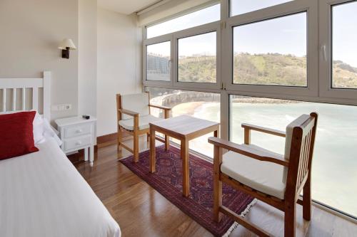 a bedroom with a bed and a table and chairs at Saiaz Getaria Hotela in Getaria