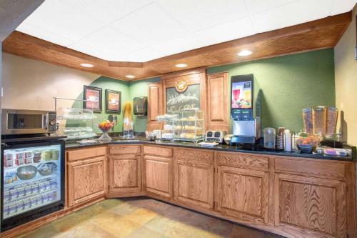 een grote keuken met houten kasten en een koelkast bij AmericInn by Wyndham Hayward in Hayward