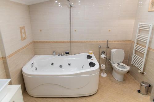 a bathroom with a bath tub and a toilet at Семеен Хотел Олимп in Sopot