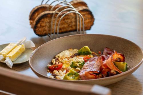 a bowl of food on a table with bread at Canopy By Hilton Cape Town Longkloof in Cape Town