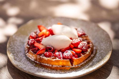 a waffle with fruit and ice cream on a plate at Canopy By Hilton Cape Town Longkloof in Cape Town
