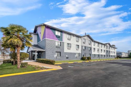 a large apartment building with a palm tree next to a street at Spark by Hilton Norfolk in Norfolk