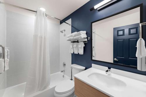 a bathroom with a white toilet and a blue wall at Spark by Hilton Norfolk in Norfolk