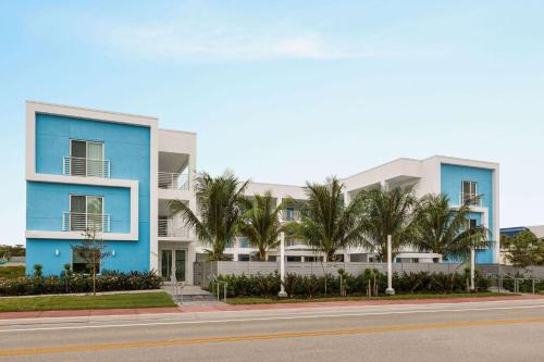 a blue building with palm trees in front of a street at Sea Glass Beach Place, Trademark Collection by Wyndham in Fort Lauderdale
