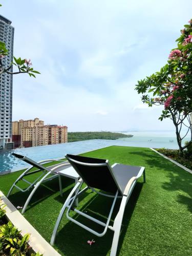 a table and chairs sitting on the grass near the water at Urban Suites George Town in Jelutong