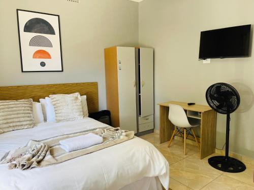 a bedroom with a bed and a desk and a television at Maita Guest in Cape Town