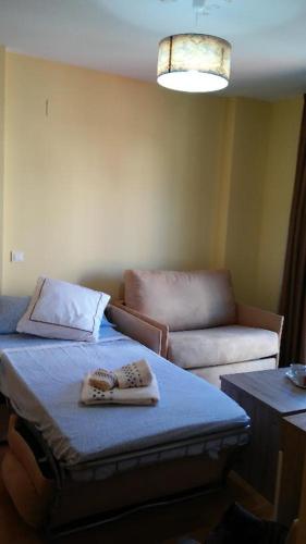 a room with two towels on a bed and a couch at Apartamentos Turísticos La Garza in Cáceres