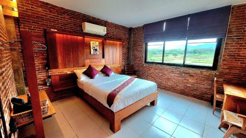 a bedroom with a bed and a brick wall at SuanGlangNa in Phrae