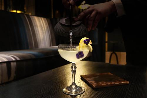 a drink being poured into a martini glass on a table at Hotel Montalembert in Paris