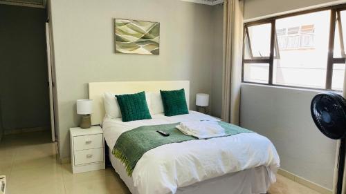 a bedroom with a bed with green and white pillows at Maita Guest in Cape Town