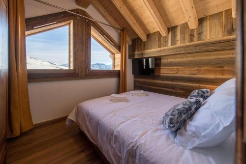 une chambre avec un lit dans une pièce avec une fenêtre dans l'établissement ODYSSEE A201 Vaste appartement en vieux bois sur les pistes, vue panoramique, à La Toussuire