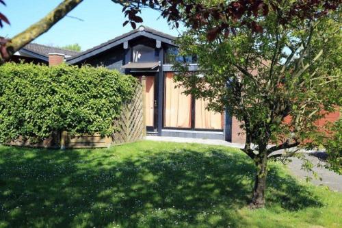 a house with a tree in front of a yard at Ferienhäuser Fedderwardersiel Am Yachthafen 93 in Fedderwarderdeich