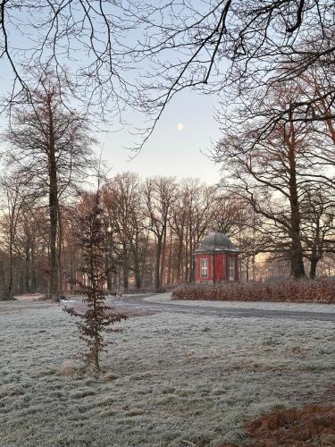 a small tree in a field with a red building at La Folie in Modave