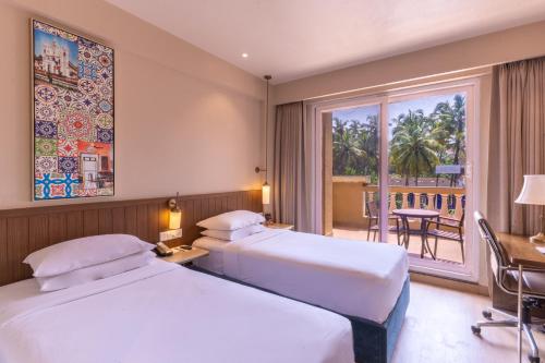 two beds in a hotel room with a balcony at Fairfield by Marriott Goa Calangute in Calangute