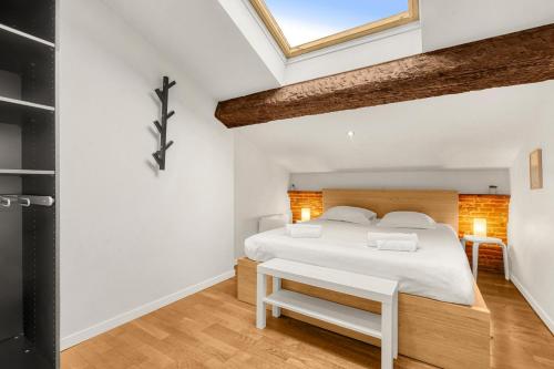 une chambre avec un lit blanc et une lucarne dans l'établissement Le Charmeur - Proche Place du Capitole, à Toulouse